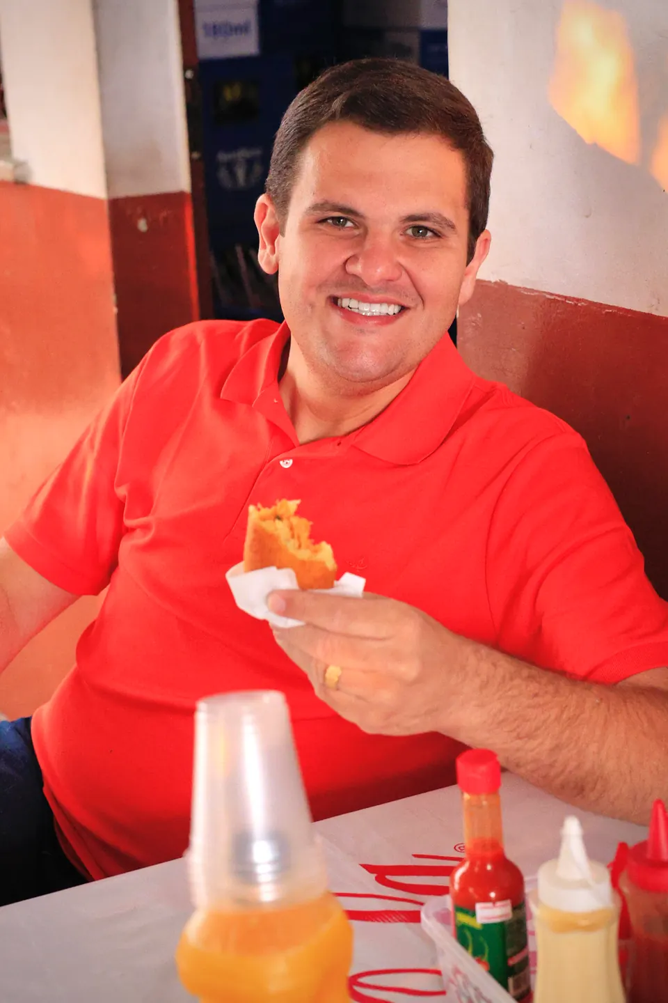 Renato Junior sorri sentado à mesa durante um lanche