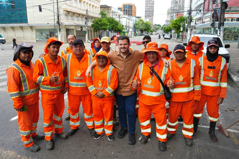 Renato Junior com agentes de limpeza de uniforme laranja em uma rua do Centro