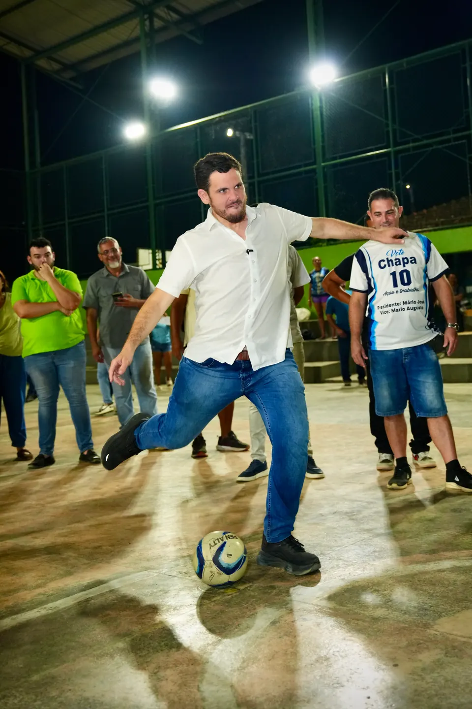 Renato Junior chuta uma bola em uma quadra iluminada à noite